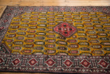 Angled view of a vintage Romanian rug with a gold boteh field and red stepped medallion.