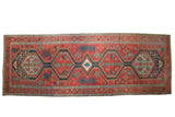 A collector's antique Serapi runner with a single column of medallions on a rich brick-red ground.