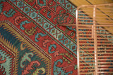 Detail of the antique Serapi's expressive leaf motifs in brick red, powder blue, and copper green.