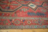 Bold geometric medallions and stylized florals on the brick red ground of an antique Serapi rug.
