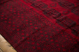 Charcoal navy Bokhara guls and geometric border on a vintage Ersari rug's rich red pile.