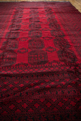 A low-angle perspective on the full, dense pile of a vintage red Ersari carpet.