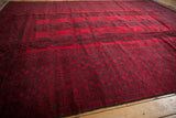 Full length angled view of the Ersari design carpet's rich red pile and charcoal navy guls.