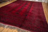 Angled view of a vintage Ersari carpet with repeating charcoal guls on a saturated red ground.