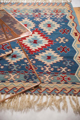 Hand woven Turkish Kilim with geometric medallions and rolling wave motif in blue, red, sand.