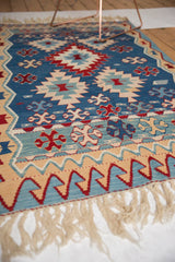 Vintage Turkish Kilim rug end, featuring beige fringe and red, blue reciprocating wave motif.