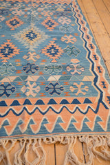 Turkish Kilim rug end showing hand woven fringe and border patterns in apricot, blue, ivory.
