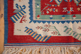 Abstract human figures and green plant motifs on the cherry red field of a vintage Turkish Kilim.