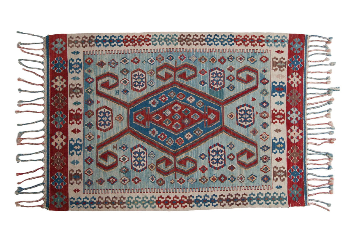 Vintage Turkish Kilim rug with a red and blue geometric medallion, ram's horn motifs, and abrashes on a powder blue field.