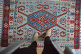 Vintage Turkish Kilim showing the dramatic geometric medallion with rams horn motifs in red, blue, and ivory.
