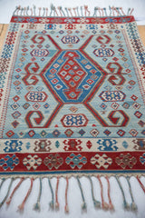 Angled view of a vintage Turkish Kilim rug showing its complete geometric design and fringe.