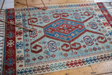 Angled view of a vintage Turkish Kilim showing its dramatic medallion and geometric borders in red and blue.