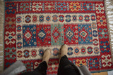 Hand woven Turkish Kilim rug with vibrant red, blue, and ivory geometric patterns underfoot.