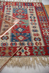 Colorful hand woven vintage Turkish Kilim rug section with geometric gul motifs and fringe.