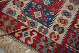 Hand woven vintage Turkish Kilim rug detail, showing vegetable dye patterns, floral motifs, and fringe.