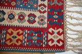 Vintage hand-woven Turkish Kilim corner with red, blue, ivory geometric patterns, selvage, and fringe.