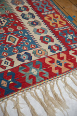 Natural ivory fringe, cherry red, and sky blue geometric Kilim pattern.