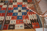 Hand woven Turkish Kilim rug's finned pattern with snowflake motifs in red, blue, ivory.