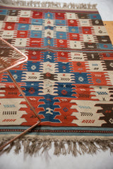 Fringe and geometric paneled motifs of a hand-woven Turkish Kilim rug with natural dyes.