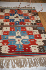 Vintage Turkish Kilim rug, angled showing paneled finned and gul motifs in natural red, blue, ivory.