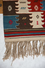 Vintage Turkish Kilim rug corner with paneled finned motifs, striped border, and natural fringe.