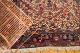 Corner detail of a vintage Mehrivan carpet showing the intricate navy border and full ivory fringe.