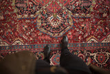 Scalloped navy medallion and delicate vinery on the cherry red field of a vintage Ahar carpet.