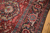 Intricate samovar and Herati floral motifs in the wide navy border of a vintage Persian Ahar carpet.