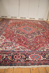 Low angle view of a vintage Ahar carpet's plush red pile and intricate navy blue border.