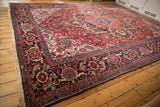Angled perspective of a vintage Ahar rug's cherry red field and wide, dark Herati-style border.