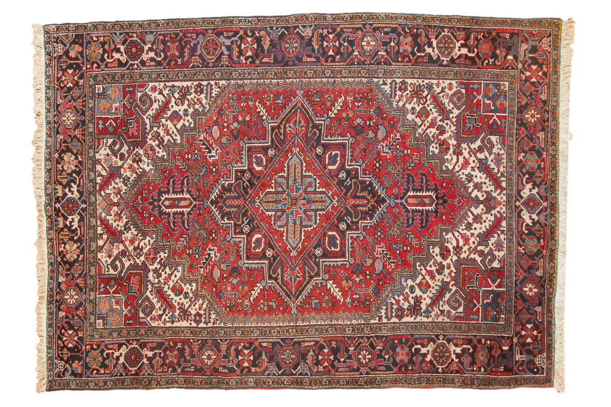 Vintage Persian Heriz carpet with concentric medallions in brick red, charcoal, and sky blue.