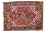 Vintage Persian Heriz carpet with concentric medallions in brick red, charcoal, and sky blue.