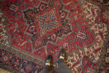 A perspective view of the vintage Heriz's geometric medallion in brick red, navy, and powder blue.