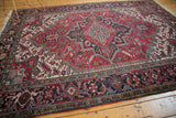 Angled view of a vintage Heriz carpet highlighting its bold geometric medallion and navy blue border.