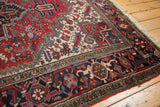 Corner view of a vintage Heriz carpet showing its geometric border, intact side cord, and fringe.