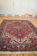 Vintage Heriz carpet with a bold geometric medallion and layered borders, viewed from an angle.