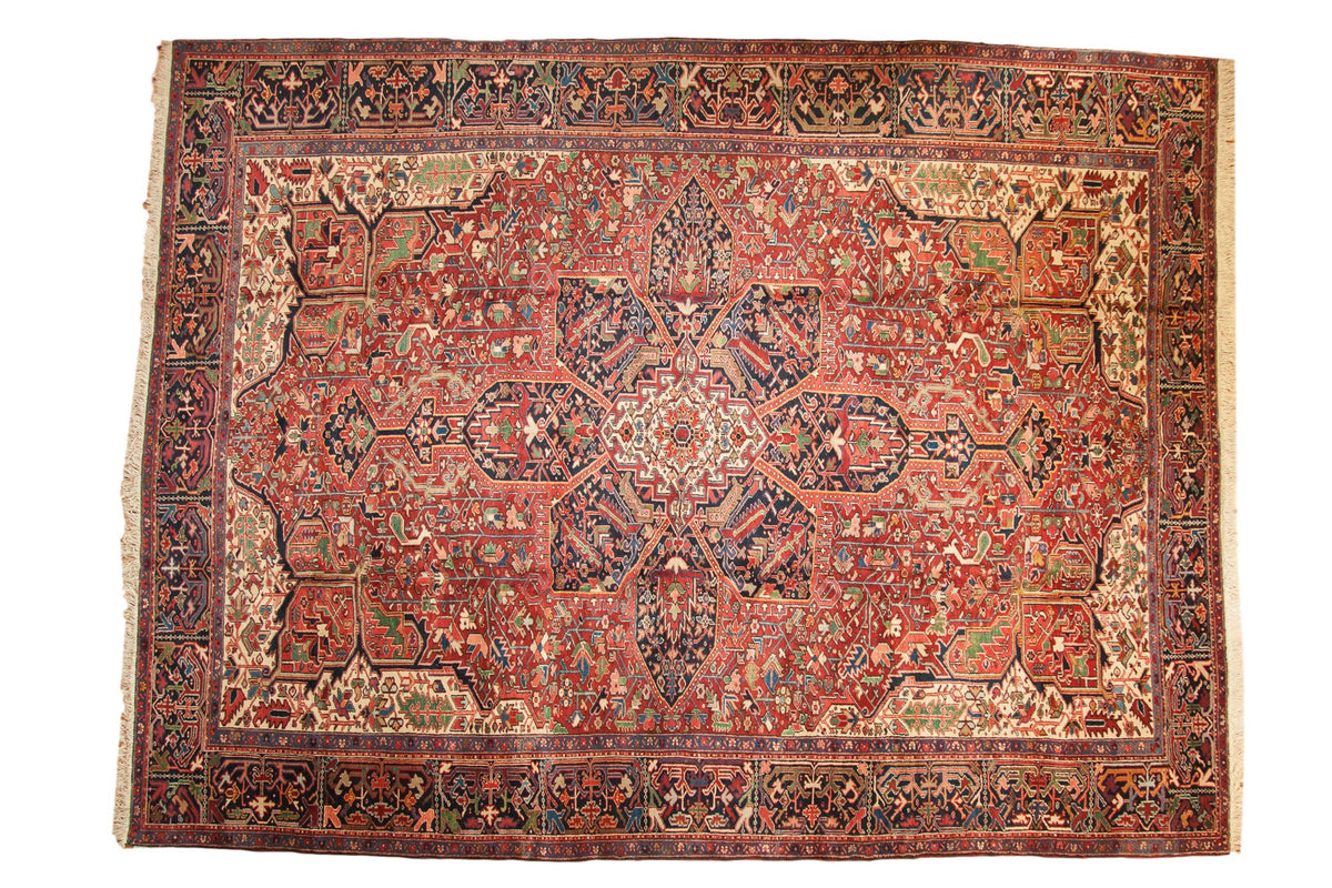Vintage Heriz carpet with a bold starburst medallion and geometric field in cherry red and navy blue.