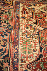 Angled view of the plush wool pile and geometric floral motifs on a vintage Persian Heriz carpet.
