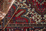 Detailed view of serrated leaf and pomegranate motifs on a lush cherry red Persian rug.