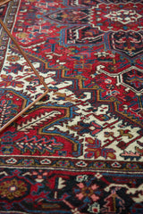 Detailed view of the vintage Persian carpet's pomegranate motifs and plush, cherry-red pile.