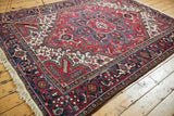 Angled room view of a vintage Mehrivan carpet showcasing its traditional cherry red and navy blue pattern.