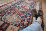 In-home view of a vintage Ardebil runner's geometric medallions and navy blue field.
