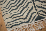 Fringed end of a vintage Indian handwoven kilim rug featuring ivory and charcoal zebra stripes.