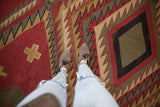Hand woven Soumac carpet detail with serrated geometric patterns in red, green, and beige.