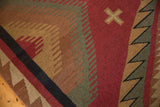Hand-woven Indian Soumac rug detail showing serrated red, beige, and green geometric patterns.