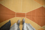 Vintage contemporary Kilim rug with terracotta and sand Argyle diamond pattern, showing feet.
