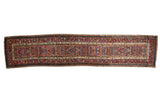 Antique Serab rug runner with a field of dense floral arrangements and suggested medallions in red, blue, and camel.