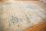 Low angle view across the distressed surface of a vintage Bulgarian rug in ivory, blue and gold.