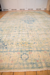 Angled view down the length of the distressed vintage rug, showing the faded Herati pattern and low-pile texture.