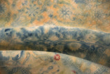 Worn pile of a distressed vintage carpet showing the hand-knotted foundation in soft folds of blue and gold.